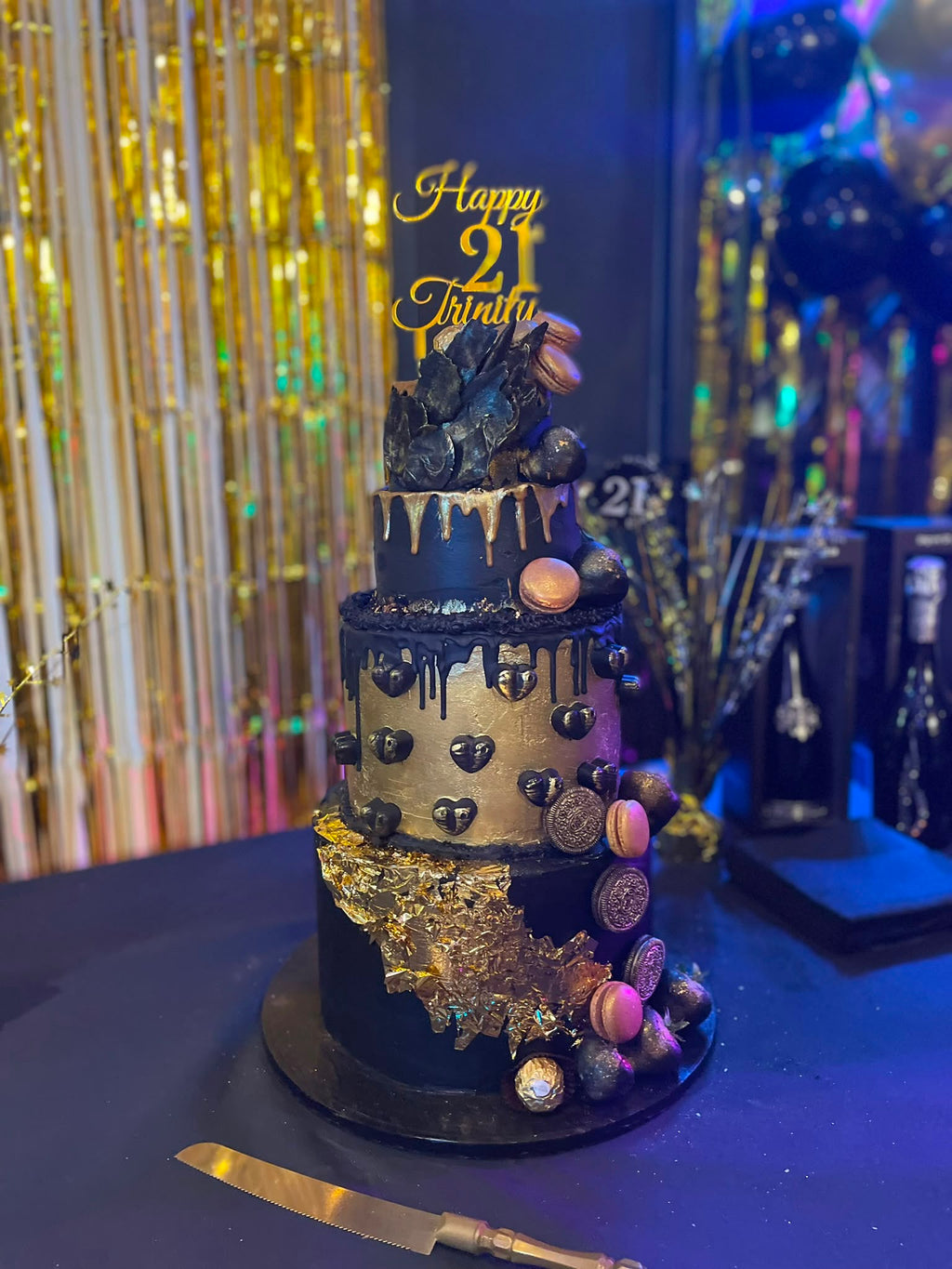 Luxe handgemaakte verjaardagstaart van Cake Magic met zwarte drip, bladgoud, macarons, chocolade, koekjes en gouden topper, speciaal ontworpen voor een 21e verjaardag in Schiedam.
